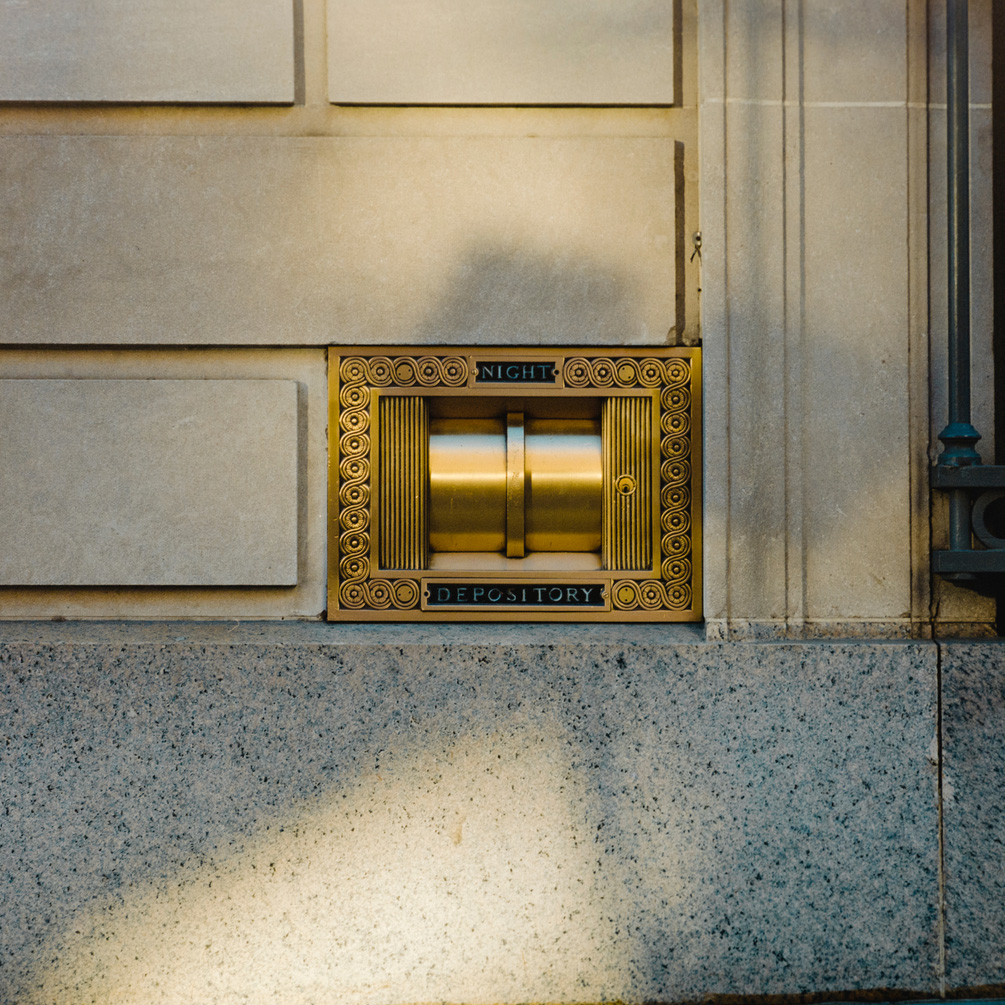 Brass night deposit box on the outside wall of a bank