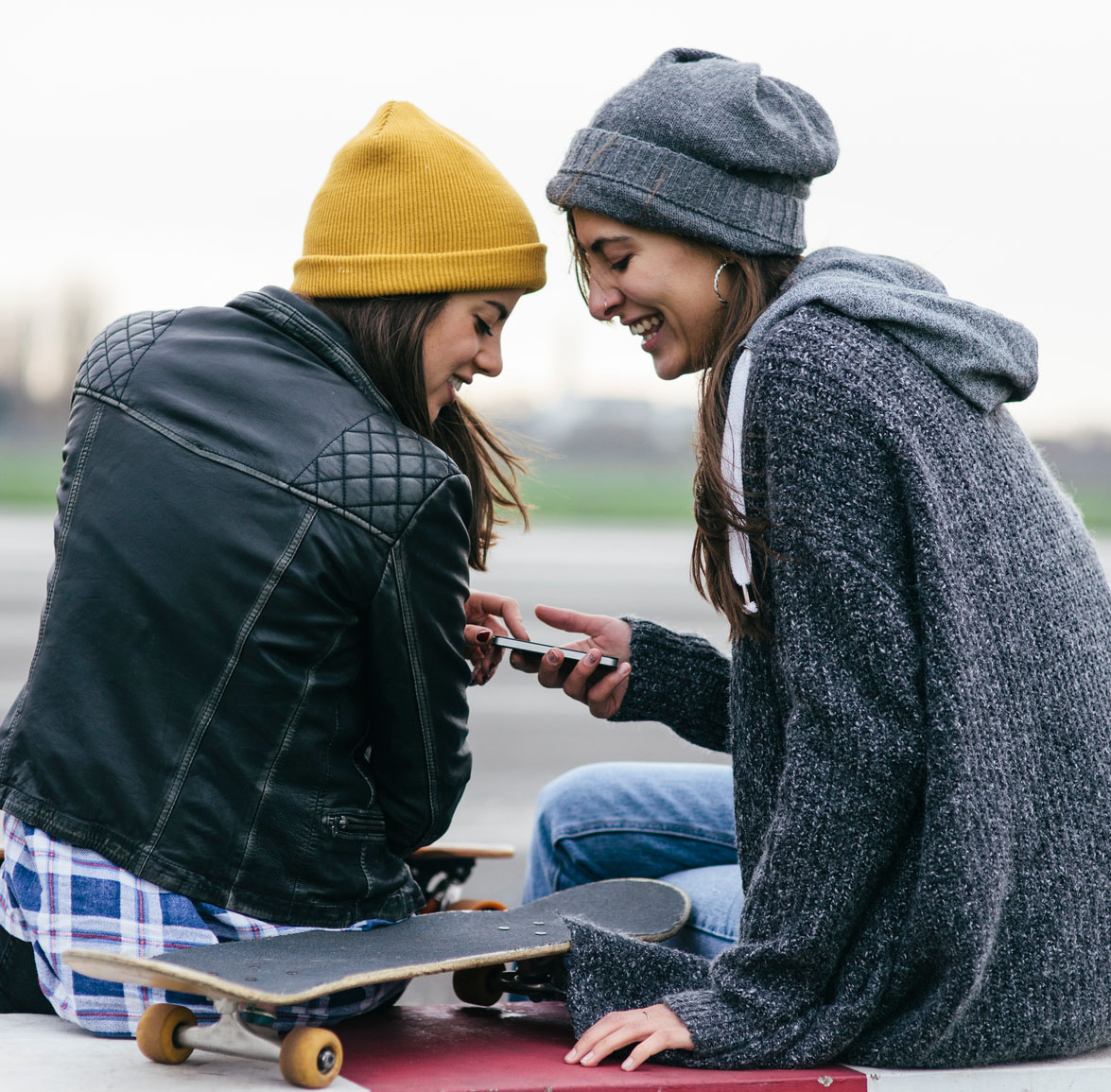 Two friends sharing a text message on a cellphone.
