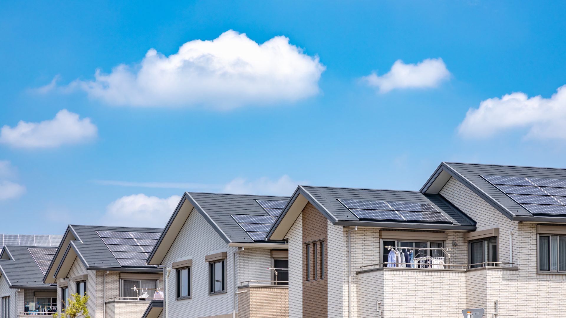 Row of houses with solar panels in front of a blue sky