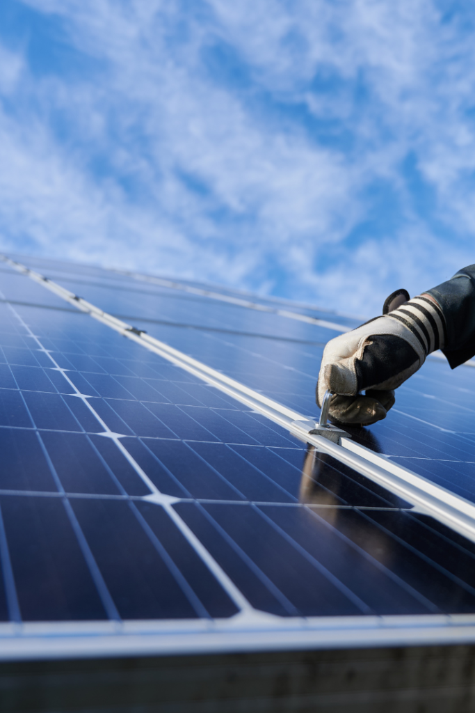 Close up photo of solar panels with a gloved hand tightening a bolt