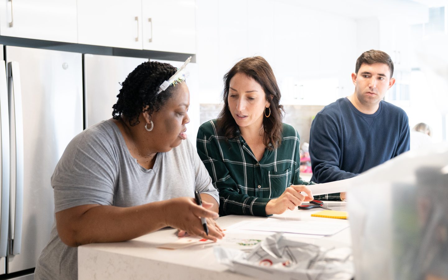 Two Forbright employees, a white woman and a black woman, talk with each other while another male employee stands in the background.