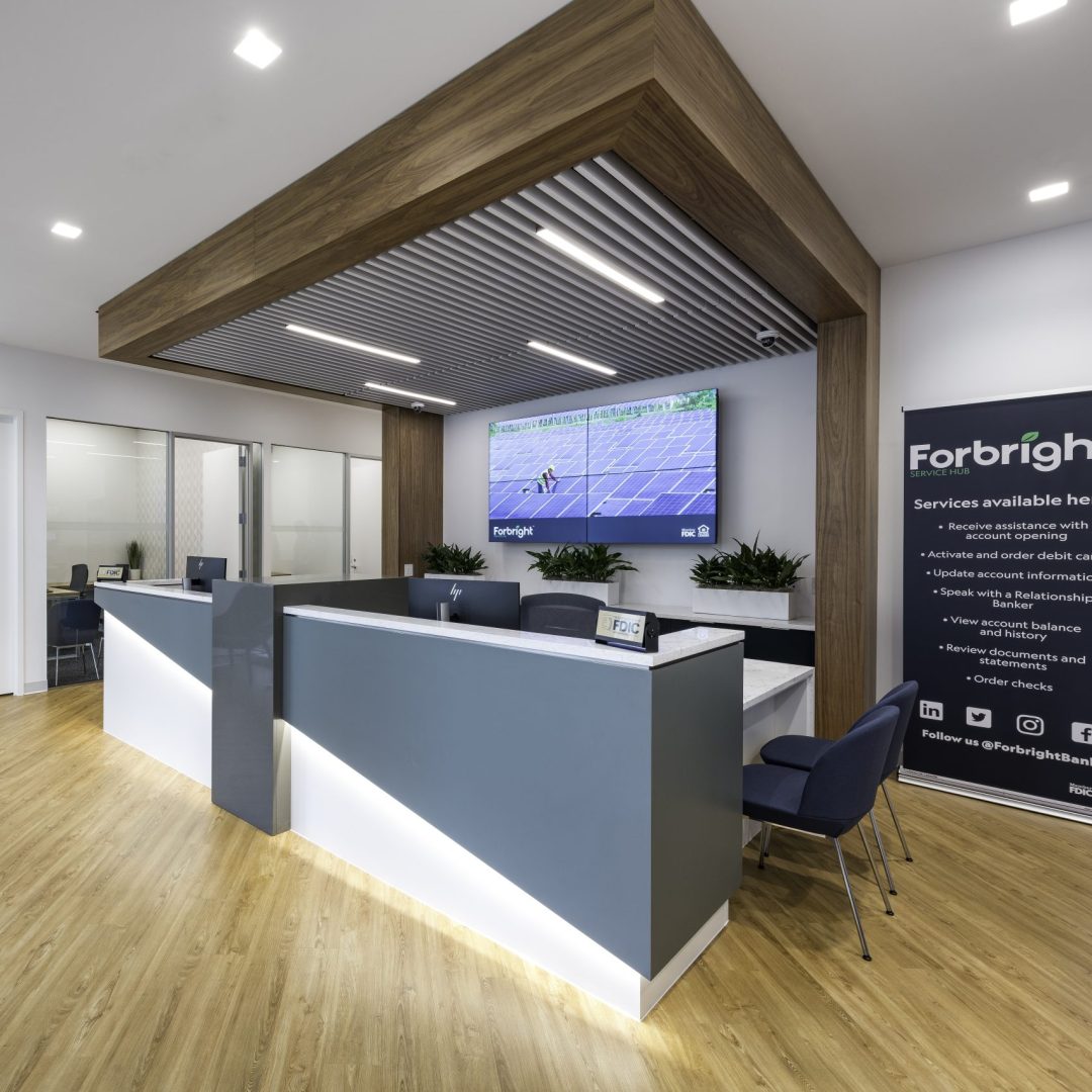 The inside of a Forbright Bank service hub showing the front desk, and private offices in the background.
