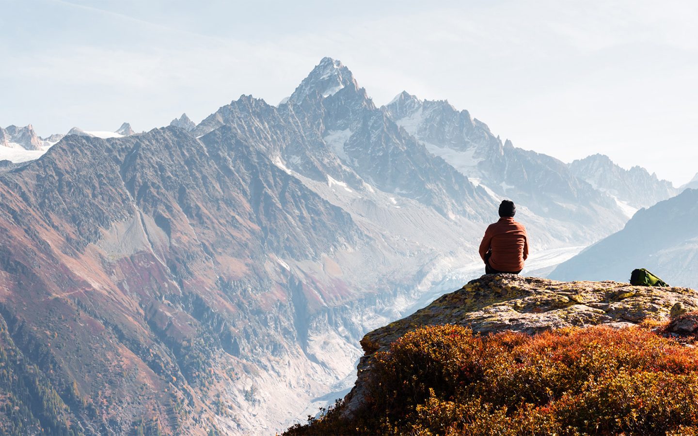 Man sitting and viewing a landscape in autumn colors, with snowy mountain in distance