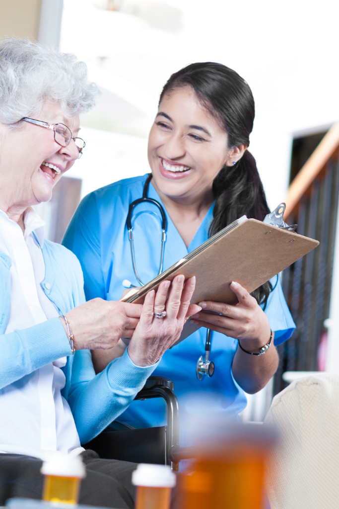 Older woman with female nurse smiling while reading a clipboard.