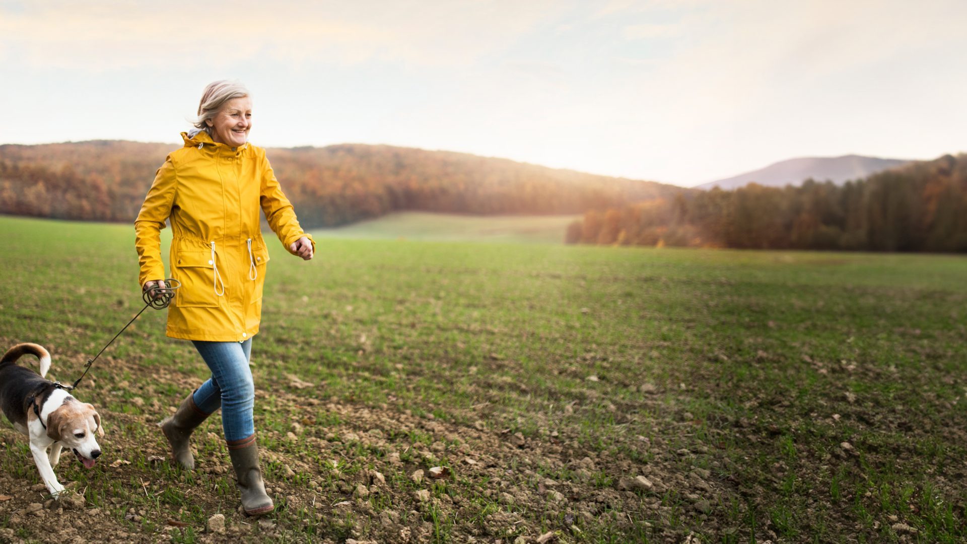 Active senior woman with dog on a walk in a beautiful autumn nature.