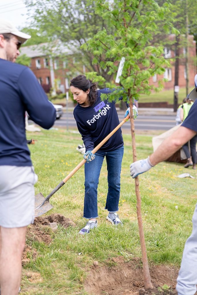 Natalie Chapman, Director of Community Impact at Forbright Bank, plants a tree in a park.
