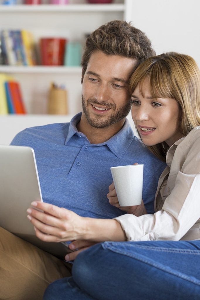 A man and woman sit together and look at a computer.