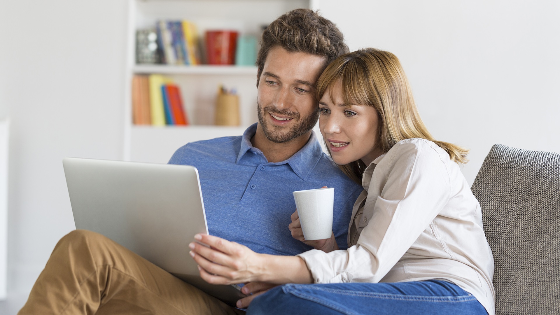 A man and woman sit together and look at a computer.