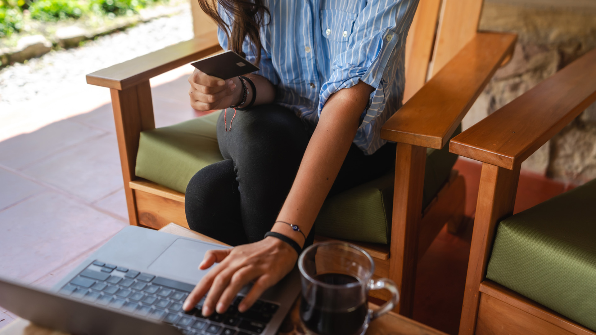 Woman's hand typing on a keyboard while she holds a credit card with the other hand.