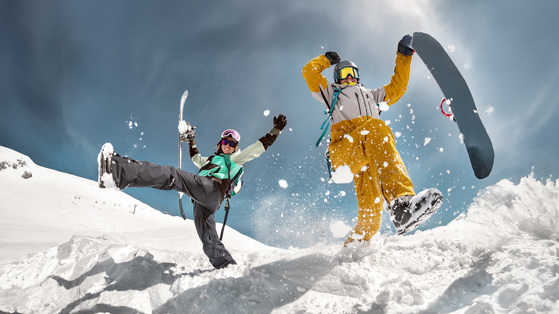 Two friends on a ski slope jumping in the snow. both are wearing heat to toe ski attire.