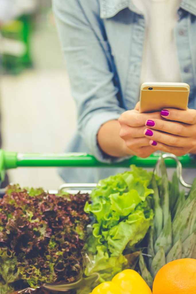 Woman on phone shopping for groceries.