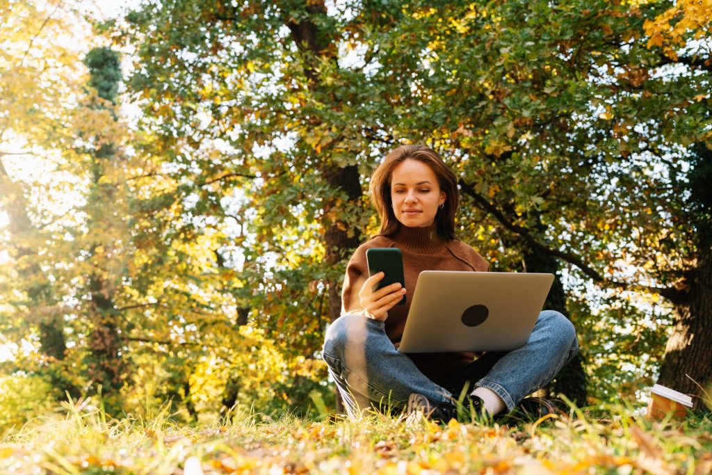 Adult woman on laptop outside in field