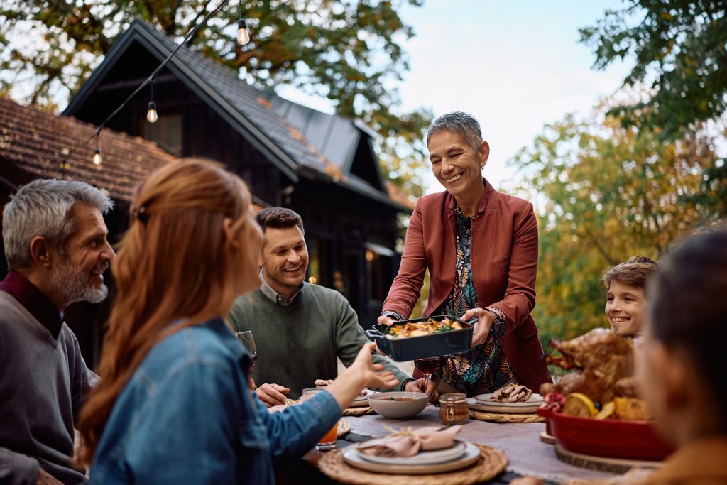 Host handing out food to group of people at table outdoors